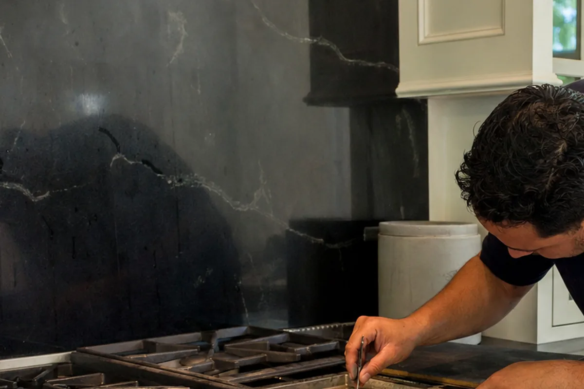 Close work on the gas cooktop half of a dual-fuel range, the burner well open and the grate set aside